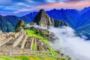 Imagen de las impresionantes ruinas de Machu Picchu en Perú, con la cordillera de los Andes y la vegetación verde exuberante en el fondo.
